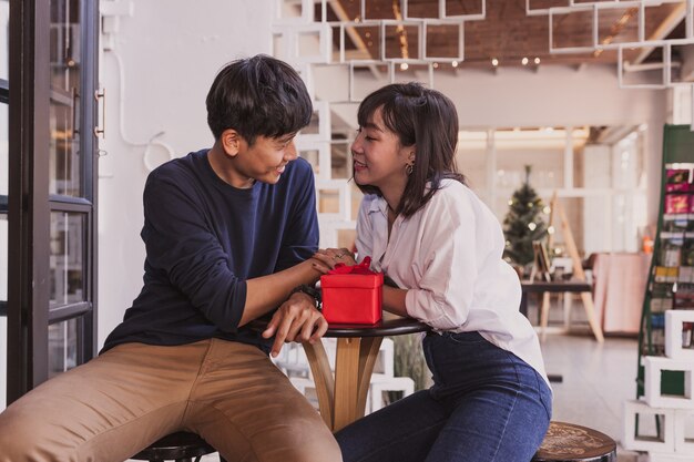 Ragazzo in amore con un regalo rosso guardando la sua fidanzata