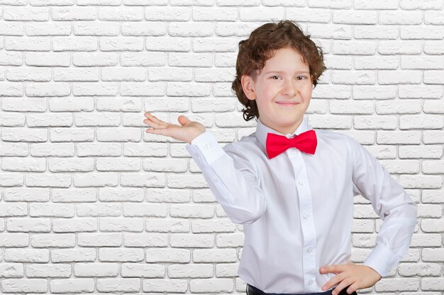 Ragazzo in camicia che indica con il palmo della mano