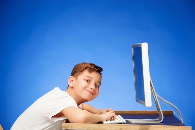 Ragazzo in età scolare che si siede davanti al computer portatile del monitor