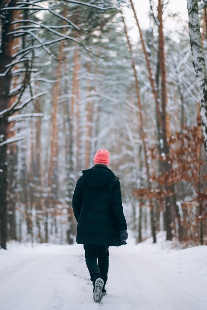 Ragazzo in piedi sulla strada in mezzo alla foresta circondato dalla neve