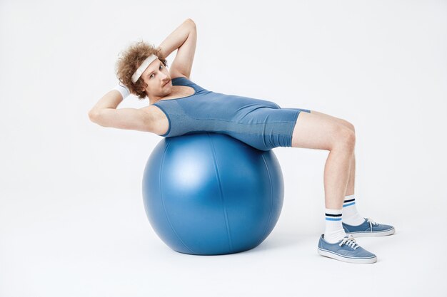 Ragazzo in tuta blu lavorando sui muscoli della pancia