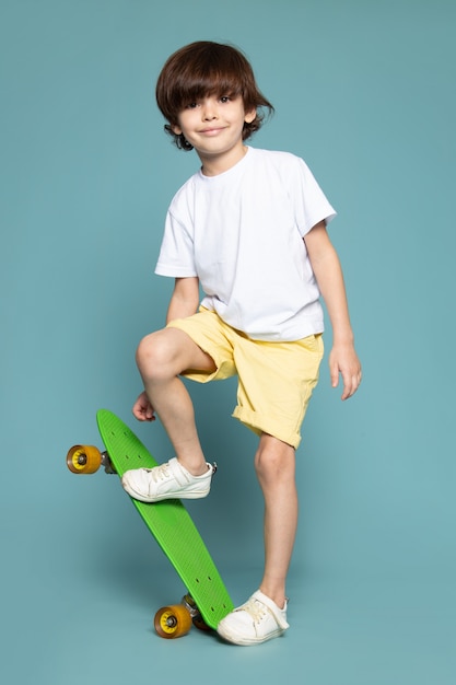 ragazzo litte in maglietta bianca che tiene skateboard sul blu