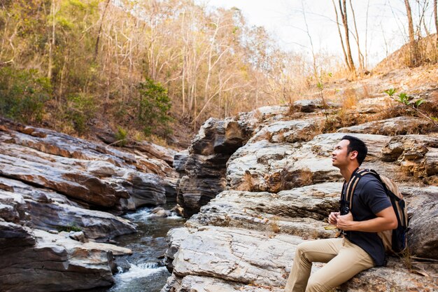 Ragazzo seduto sulle rocce vicino al fiume