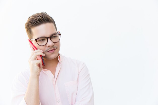 Ragazzo serio in occhiali discutendo problemi sul cellulare