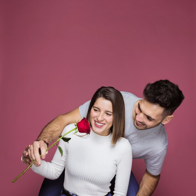 Ragazzo sorridente che presenta fiori freschi a attraente signora allegra