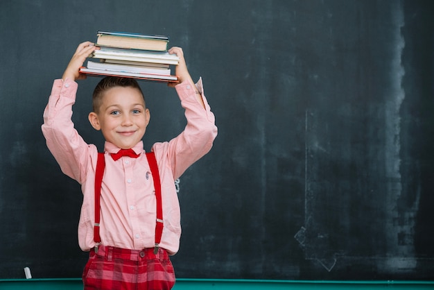 Ragazzo sorridente con i libri sulla lavagna