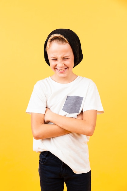 Ragazzo sorridente con le braccia incrociate che indossa cappello