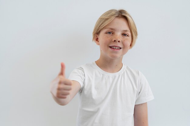 Ragazzo sorridente di vista frontale che mostra i pollici in su