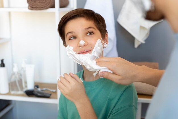 Ragazzo sorridente di vista laterale con crema da barba