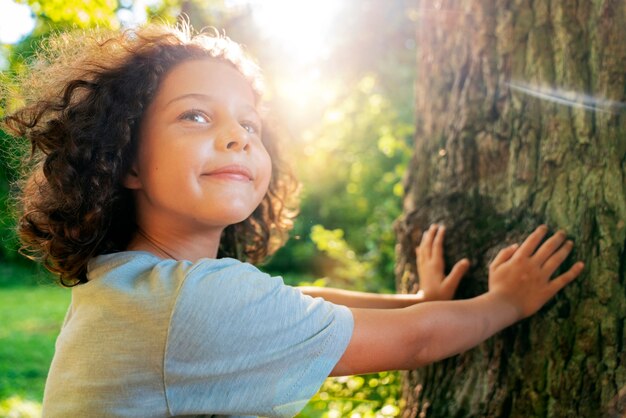 Ragazzo sorridente di vista laterale vicino all'albero