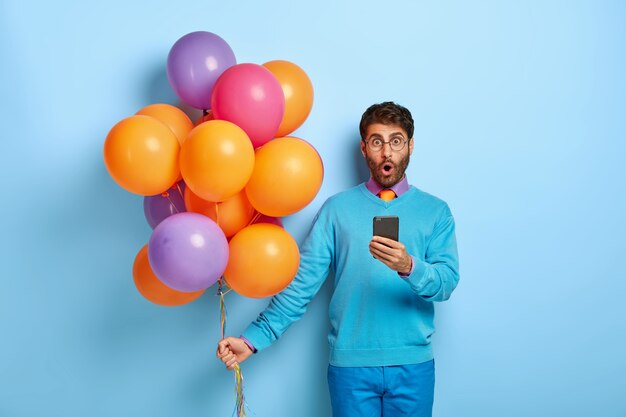 Ragazzo stupefatto con palloncini in posa in maglione blu