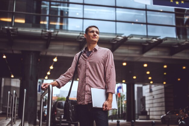 Ragazzo sulla strada moderna in abbigliamento casual con laptop