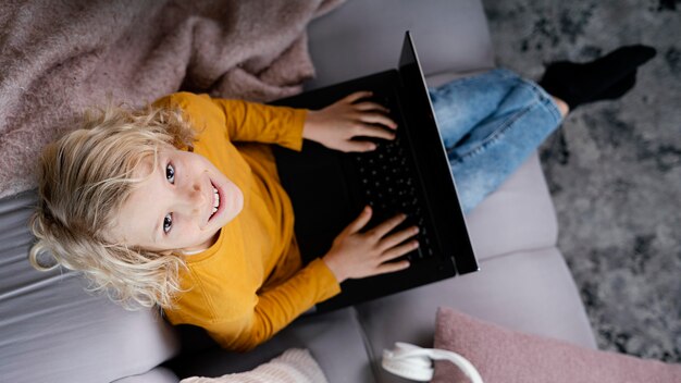 Ragazzo sullo strato con il computer portatile