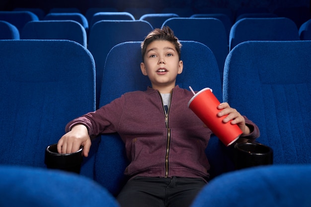 Ragazzo teso che guarda film horror nel cinema