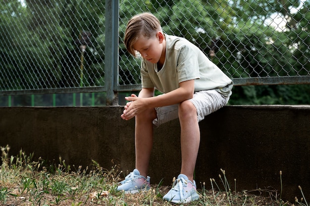 Ragazzo triste a tutto campo seduto fuori