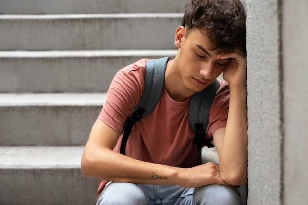 Ragazzo triste di vista frontale che si siede sulle scale