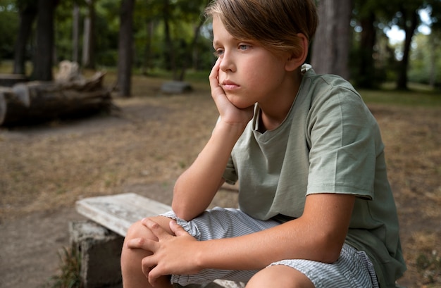 Ragazzo triste di vista laterale che si siede sulla panchina