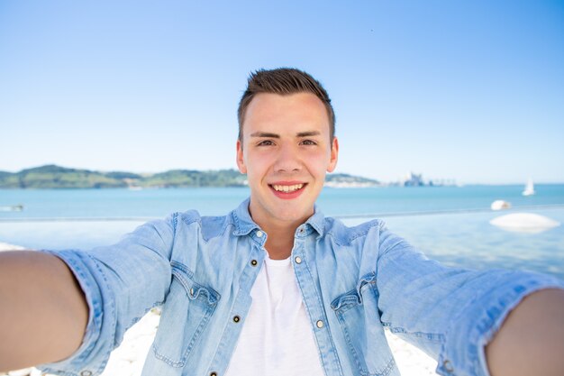 Ragazzo turistico emozionante allegro che prende selfie in mare