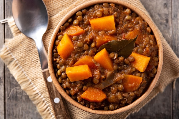 Ragù di stufato di lenticchie con zucca e carote in una ciotola sul tavolo di legno