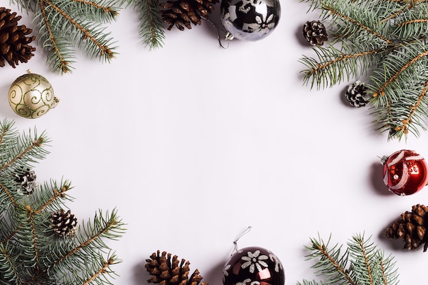 Rami attillati delle palle delle pigne della composizione della decorazione di Natale sulla tavola festiva bianca