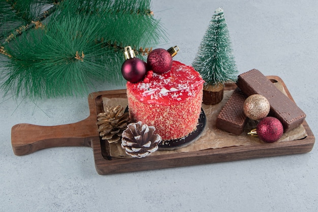Ramo di pino artificiale accanto a un vassoio di dessert assortiti su sfondo di marmo.
