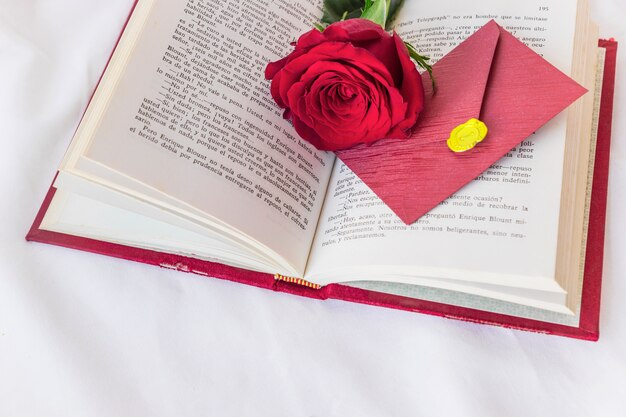 Ramo di rose rosse e busta sul libro