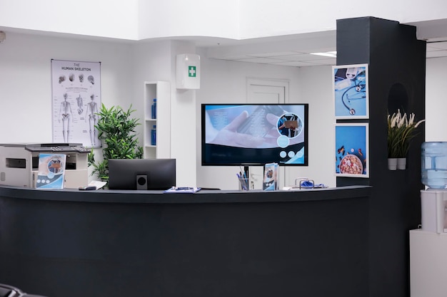 Reception dell'ospedale con computer, prenotazione di appuntamenti sanitari per pazienti con malattie. Lavoro di registrazione con referti di controllo medico e moduli di documenti nella hall della struttura.