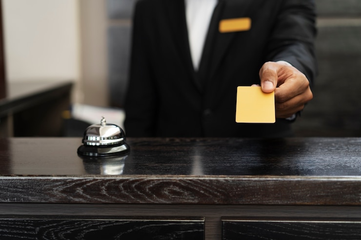 Foto gratuito receptionista in abito che offre la chiave della stanza.