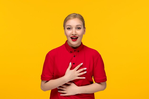 Red shirt day cutehappy ragazza che tiene il suo petto e sorridente in una camicia rossa su sfondo giallo