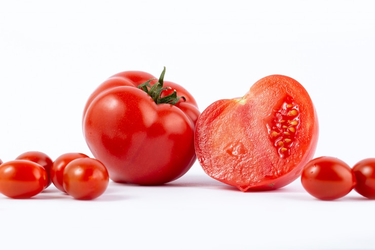 Foto gratuito red tomatoe fresco raccolto e affettato con pomodorini rossi sulla scrivania bianca