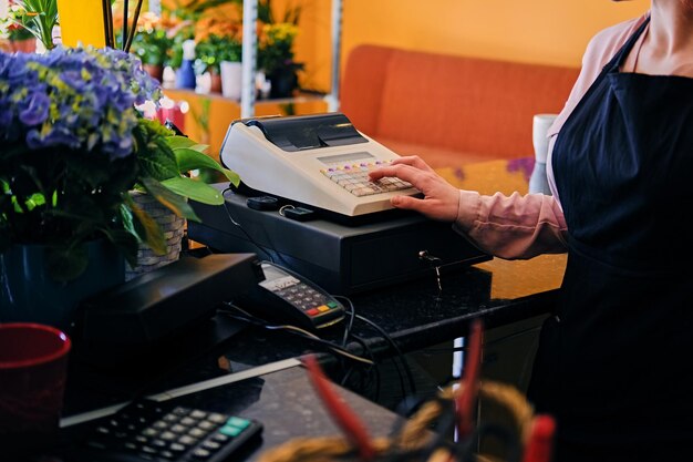 Redhead femmina venditore di fiori utilizzando il registratore di cassa in un negozio di mercato.