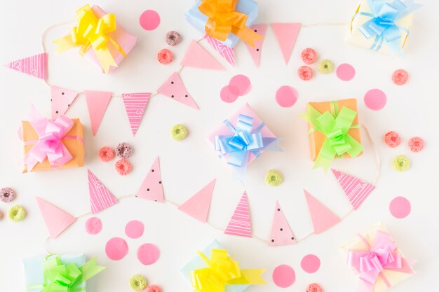 Regali di compleanno; le caramelle dei cerchi di froot e gli accessori del partito su fondo bianco