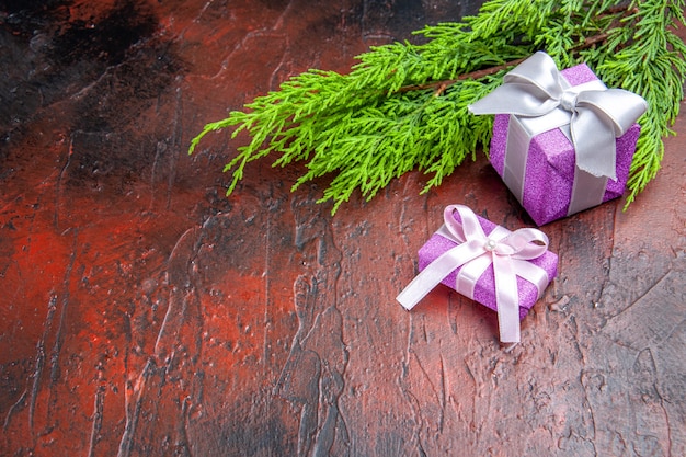 Regali di Natale vista dall'alto con scatola rosa e ramo di albero con nastro bianco su superficie rossa inglese english