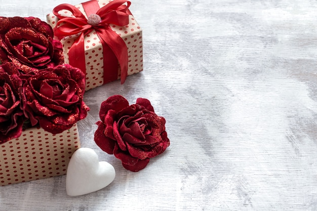 Regalo di San Valentino con rose decorative e cuore bianco su sfondo chiaro spazio copia.