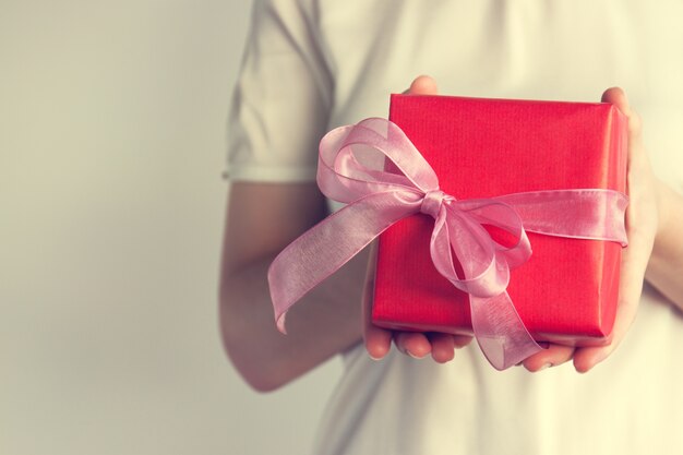 regalo rosso con un fiocco rosa tenuto da una donna