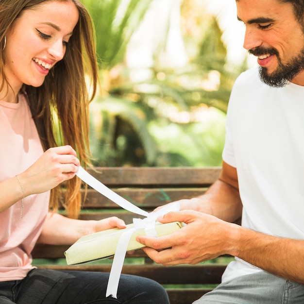 Regalo unwrapping sorridente della giovane donna comprato dal suo ragazzo