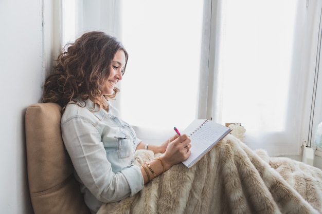 Relaxed giovane donna di scrittura sul suo notebook