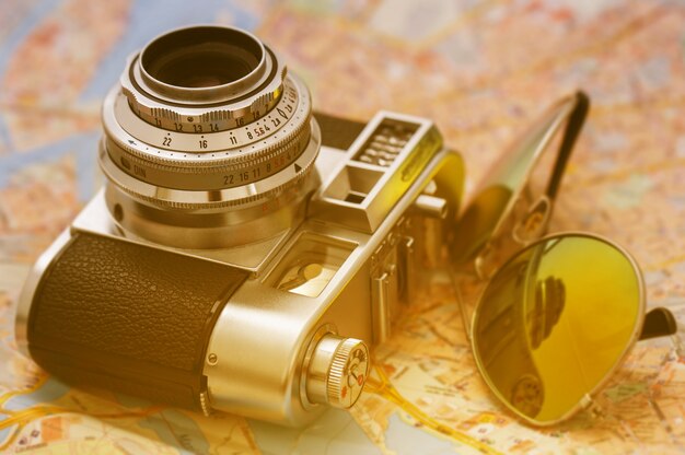 Retro macchina fotografica e occhiali da sole su una mappa