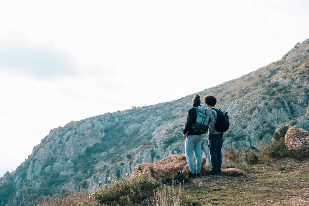 Retrovisione di giovane viandante maschio che trascura la montagna