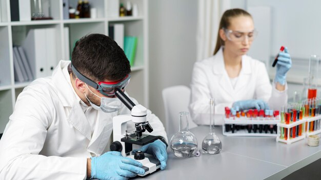 Ricercatore e collega di sesso maschile in laboratorio con provette e occhiali di sicurezza