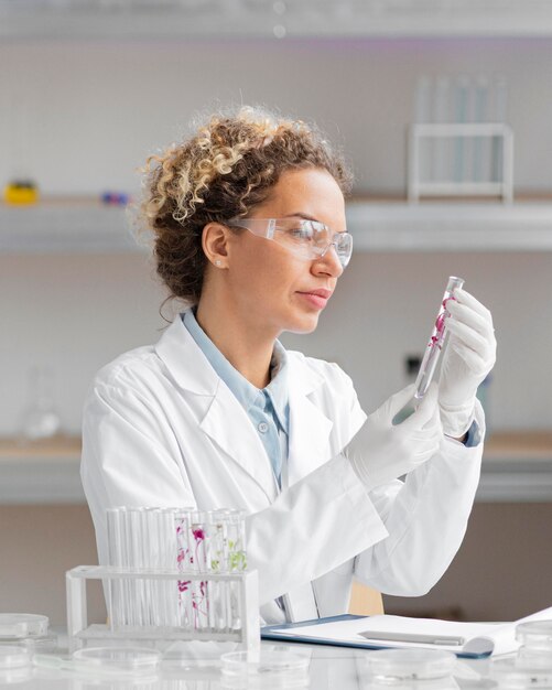 Ricercatore femminile in laboratorio con provette e occhiali di sicurezza