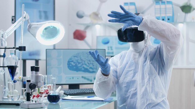 Ricercatore scienziato che indossa cuffie da realtà virtuale analizzando l'interfaccia olografica futuristica dell'attività cerebrale durante l'esperimento di chimica nel laboratorio ospedaliero di biochimica. Ricerca in neuroscienze
