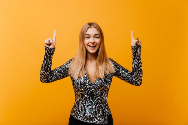 Ridendo bella donna in abito da festa agghiacciante sull'arancia. Ritratto dell'interno di splendida donna cieca in posa con un sorriso felice.