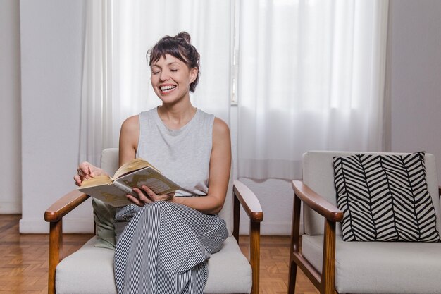 Ridendo donna moderna con libro sulla sedia