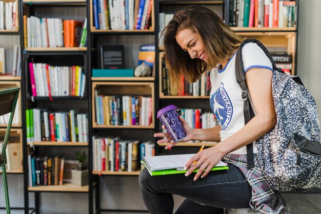 Ridendo ragazza azienda notebook su ginocchio scrittura