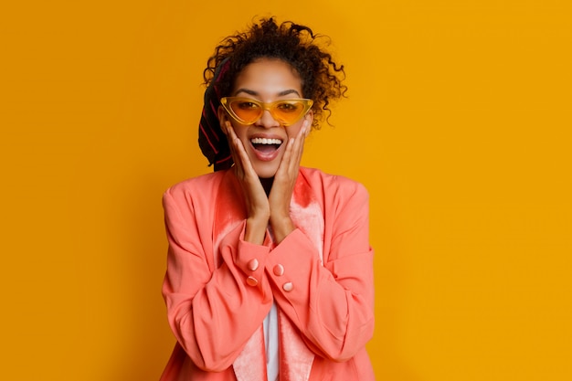 Ridere donna africana su sfondo giallo. Emozioni vere, faccia a sorpresa. Look alla moda.