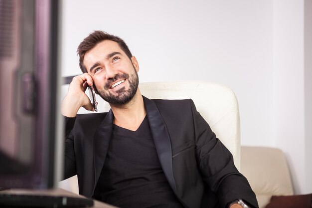 Ridere Imprenditore parlando al telefono mentre si lavora nel suo ufficio. Imprenditore in ambiente professionale