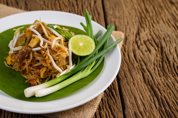 Riempia tailandese in un piatto bianco con il limone su una tavola di legno