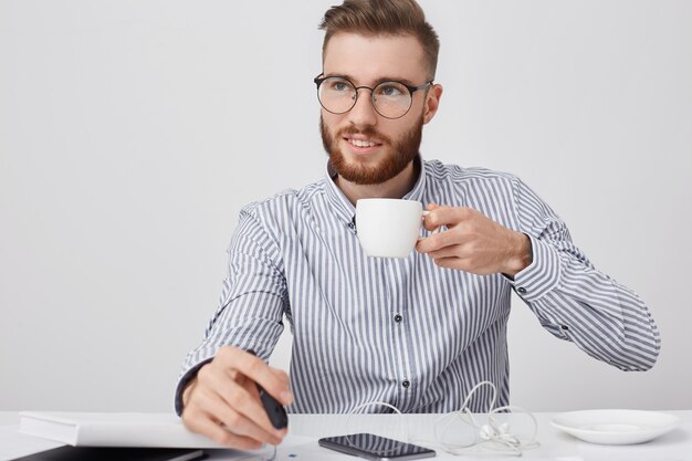 Riflessivo successo giovane uomo d'affari maschio con barba e acconciatura alla moda