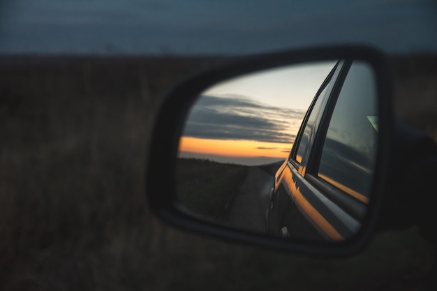 Riflesso del bellissimo tramonto attraverso lo specchietto retrovisore dell'auto